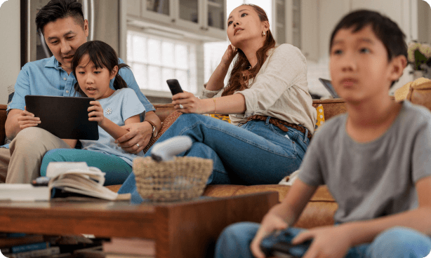 A child holding a video game controller, sitting in front of a woman watching the child play a video game