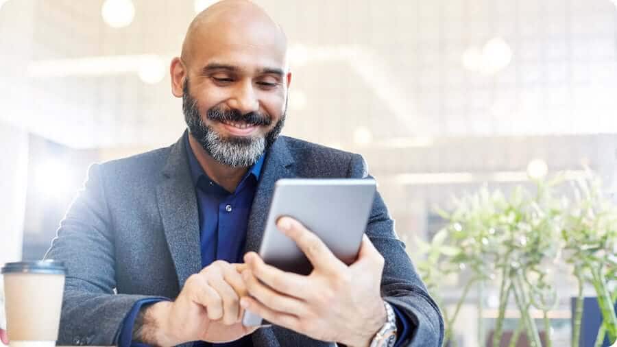 Smiling man sitting at table using wifi-enabled tablet