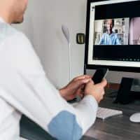 man with phone in hand looking at computer screen