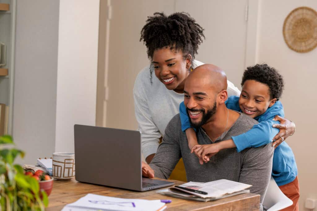 A smiling family at home looks at a computer.