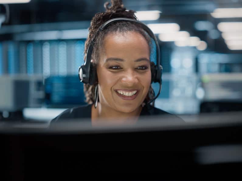 mujer mirando una computadora de escritorio mientras sonríe