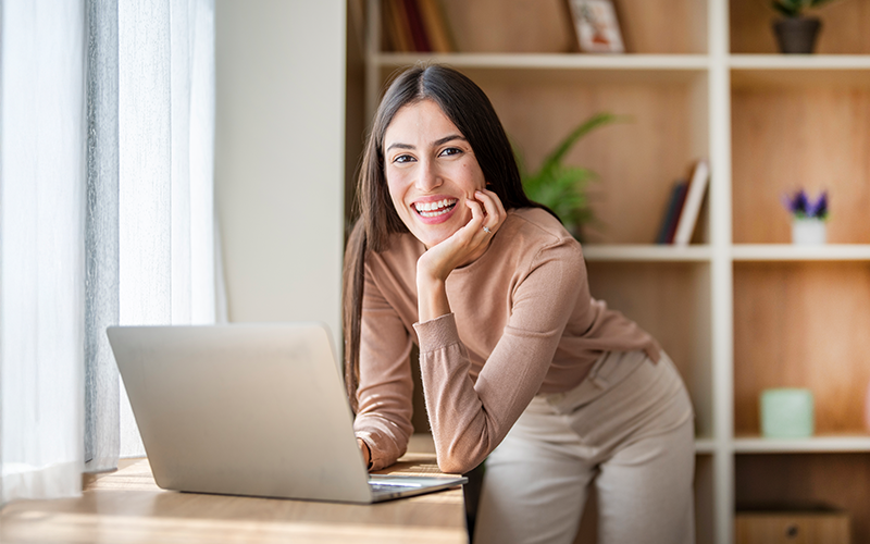 Lady leaning on desk working on a laptop