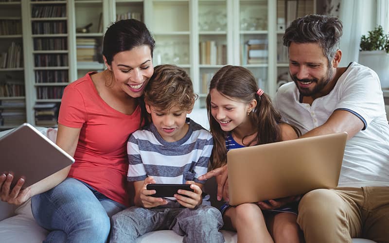 family on table, laptop and phone