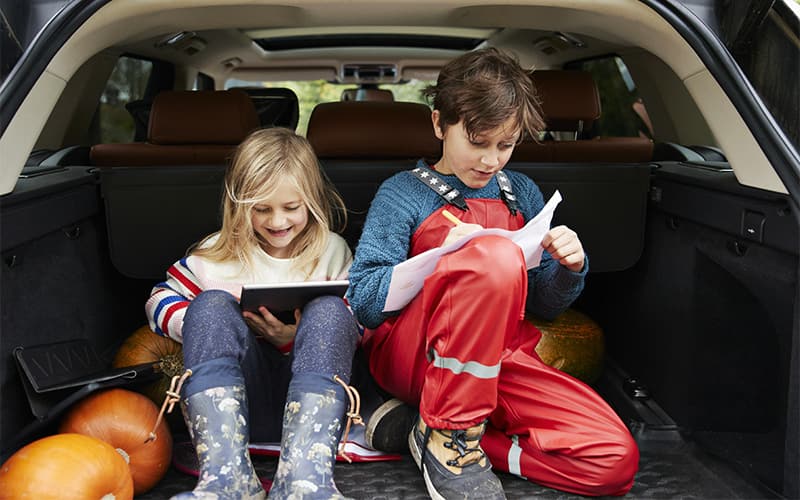 A boy and girl sitting in the car and wearing headphone