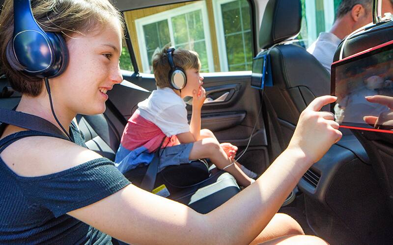 A boy and girl sitting in the car and wearing headphone