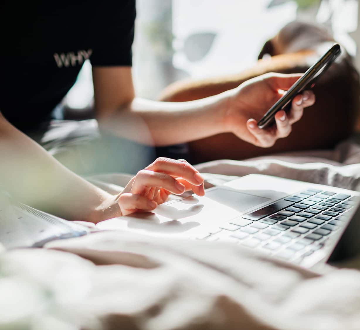 A man holding a 5G phone and typing in laptop