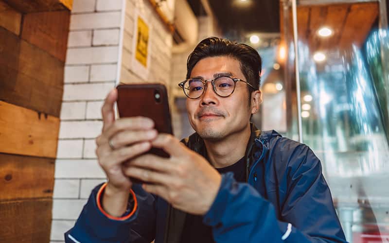 Hombre mirando un teléfono y sonriendo