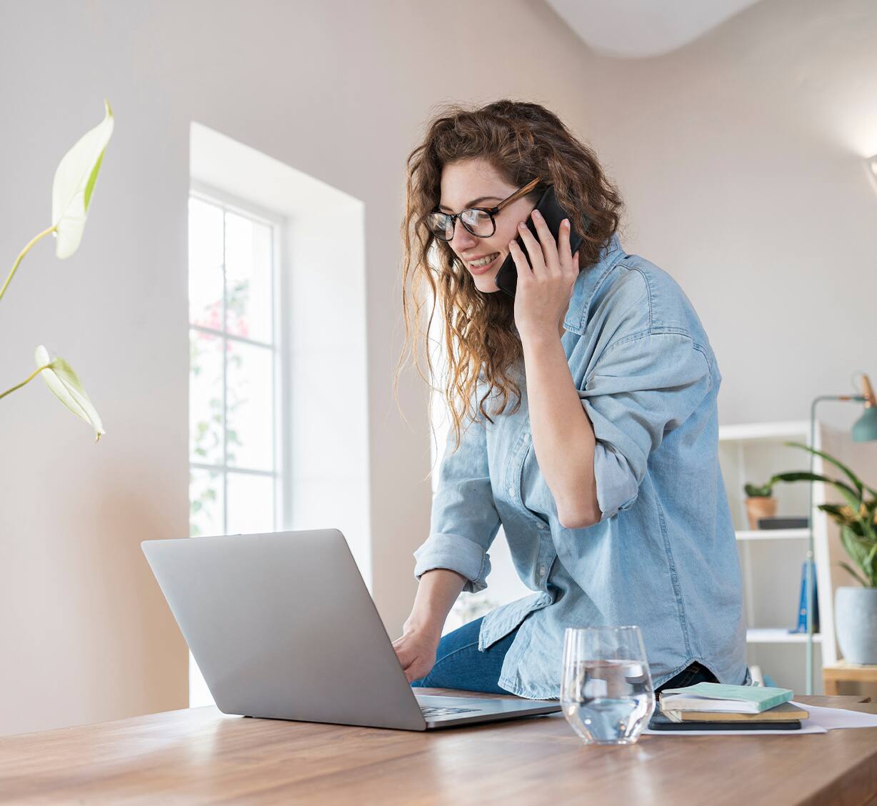 Person at desk using a laptop while speaking on a phone