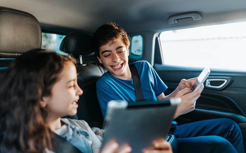 A boy and girl sitting in the car and wearing headphone